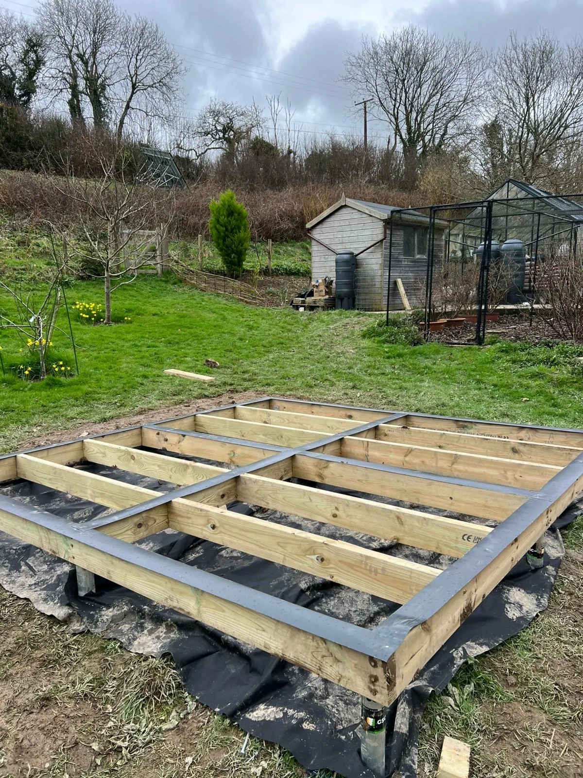 Raised timber base with visible ground screw supports on uneven ground