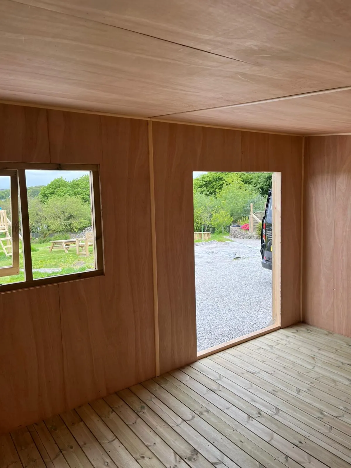 Plywood lined garden room interior with neatly finished window and door openings